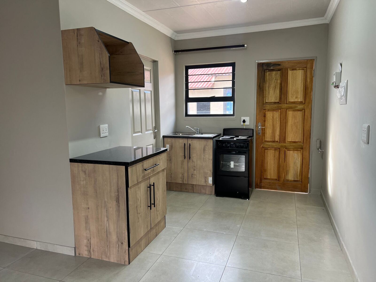 Kitchen with wood-finish cupboards, black stove and tiled floor
