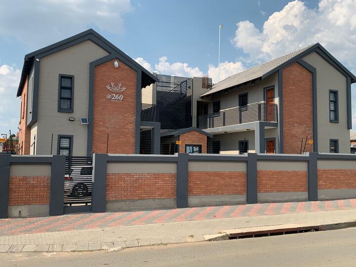 Double-storey apartment blocks at @260 Moteong behind a brick wall